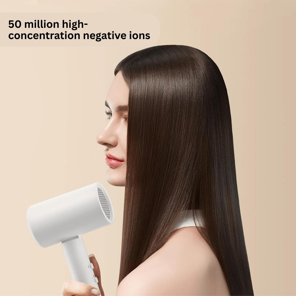 Woman with long, straight hair holding a white hair dryer against a beige background
